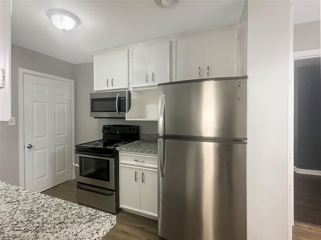 kitchen featuring stainless steel appliances, light stone countertops, white cabinets, and dark wood-style floors