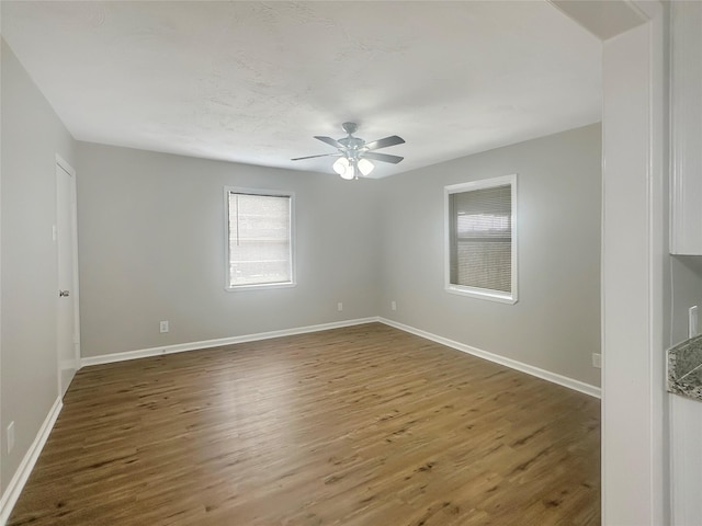 unfurnished room featuring wood finished floors, a ceiling fan, and baseboards