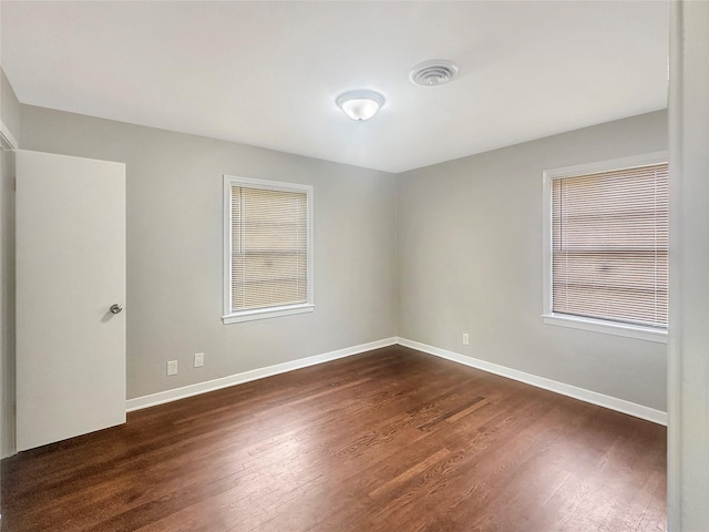 unfurnished room featuring a healthy amount of sunlight and dark wood-type flooring