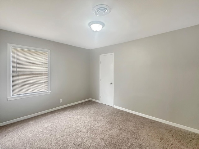 carpeted empty room featuring baseboards