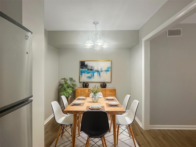 dining space with light wood-type flooring, an inviting chandelier, baseboards, and visible vents