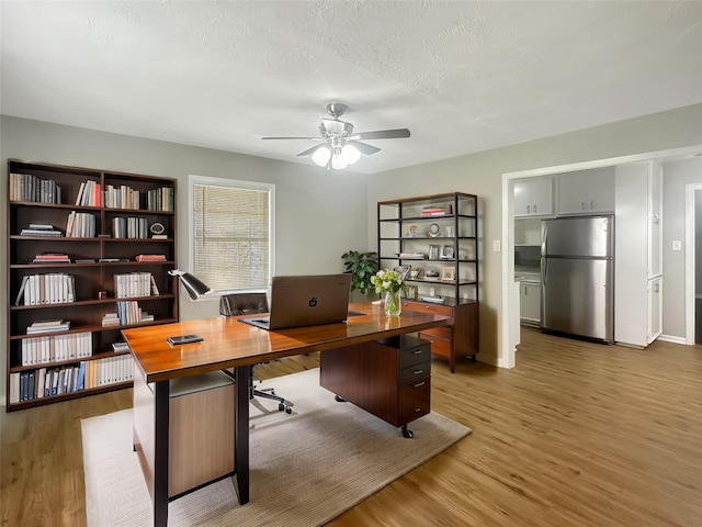 office space featuring light wood-type flooring, a textured ceiling, and a ceiling fan