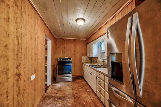 kitchen with sink, wood ceiling, white cabinetry, appliances with stainless steel finishes, and wooden walls