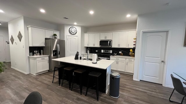 kitchen with stainless steel appliances, a center island with sink, and white cabinets