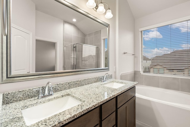 bathroom with lofted ceiling, vanity, and independent shower and bath