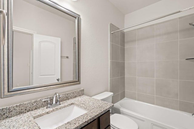 full bathroom featuring vanity, tiled shower / bath, and toilet