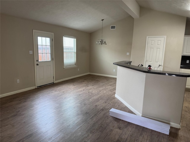 interior space with dark wood-type flooring, an inviting chandelier, lofted ceiling with beams, hanging light fixtures, and white cabinets