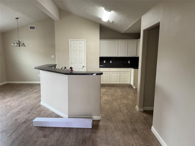 kitchen featuring dark hardwood / wood-style floors, white cabinetry, vaulted ceiling with beams, decorative backsplash, and a notable chandelier