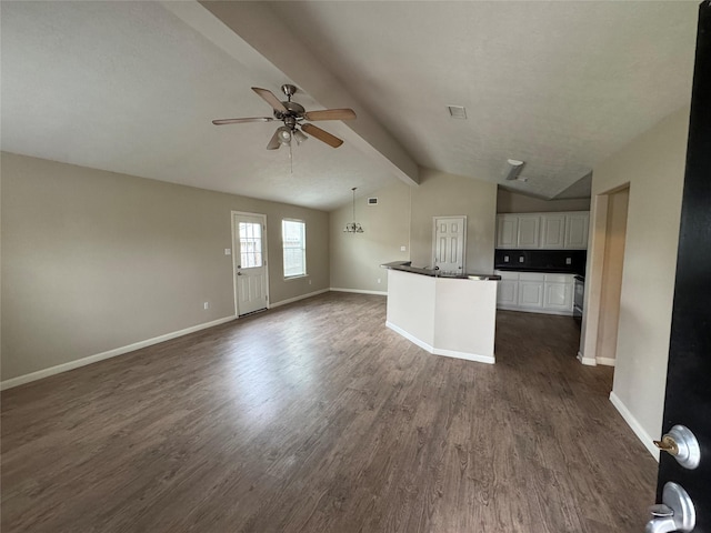 unfurnished living room with dark wood-type flooring, ceiling fan, and vaulted ceiling with beams