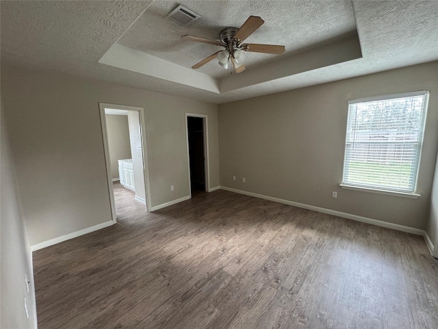 unfurnished room with dark hardwood / wood-style floors, ceiling fan, a tray ceiling, and a textured ceiling