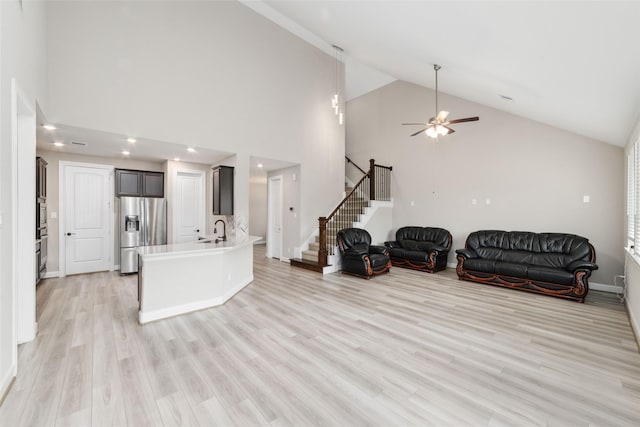 living room featuring ceiling fan, sink, high vaulted ceiling, and light wood-type flooring