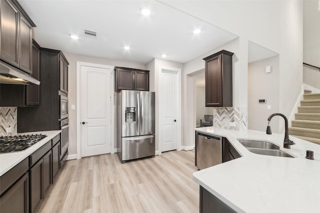 kitchen with appliances with stainless steel finishes, tasteful backsplash, sink, light hardwood / wood-style floors, and dark brown cabinets