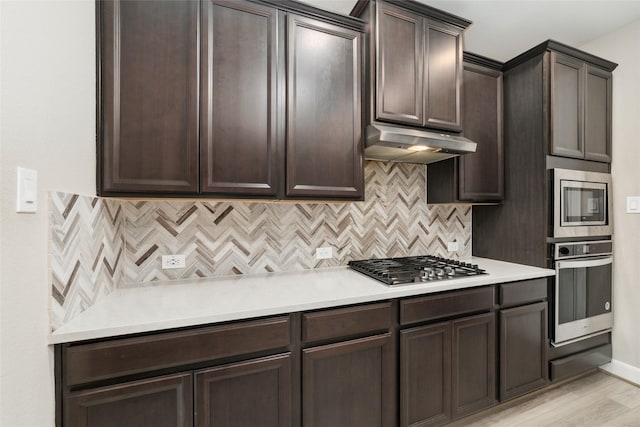 kitchen featuring dark brown cabinetry, decorative backsplash, light hardwood / wood-style flooring, and stainless steel appliances