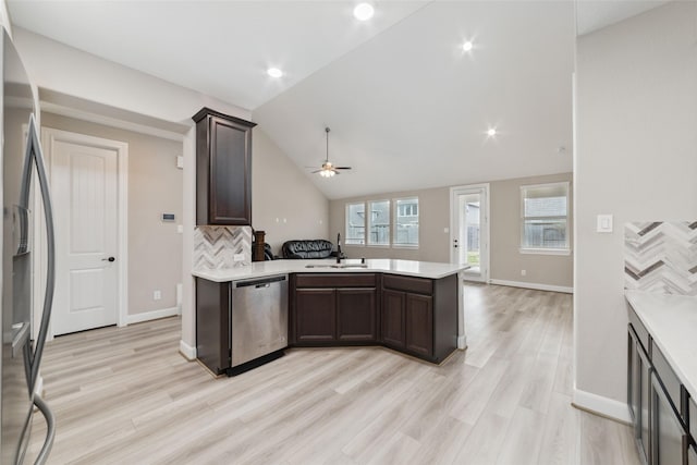 kitchen featuring lofted ceiling, sink, kitchen peninsula, stainless steel appliances, and light hardwood / wood-style flooring