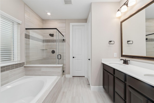 bathroom with vanity and shower with separate bathtub