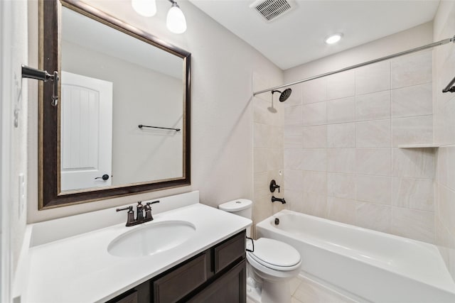 full bathroom featuring tiled shower / bath, vanity, and toilet