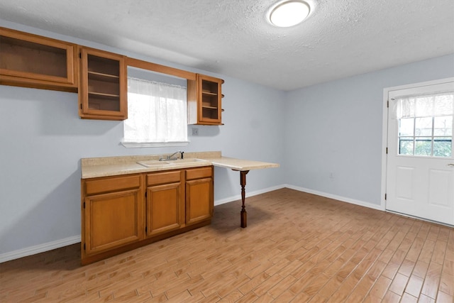 kitchen with sink, a textured ceiling, and light wood-type flooring