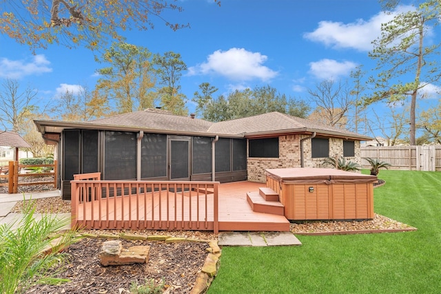 rear view of house with a hot tub, a wooden deck, a sunroom, and a yard