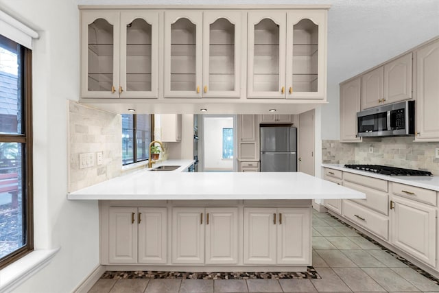 kitchen featuring tasteful backsplash, light tile patterned floors, stainless steel appliances, and kitchen peninsula