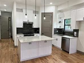 kitchen featuring dishwasher, light stone counters, white cabinets, a kitchen island, and decorative light fixtures