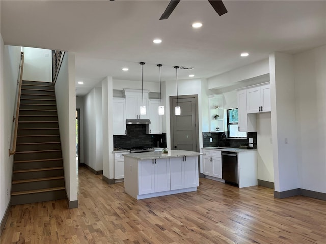 kitchen with decorative light fixtures, black dishwasher, a kitchen island, light hardwood / wood-style floors, and white cabinets