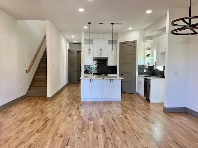 kitchen featuring sink, light hardwood / wood-style flooring, white cabinets, decorative light fixtures, and stainless steel dishwasher