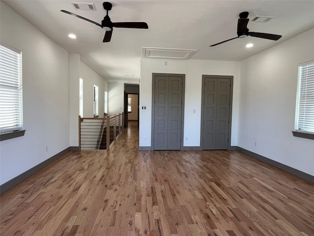 unfurnished bedroom with wood-type flooring, two closets, and ceiling fan