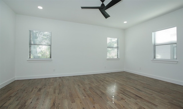 empty room featuring ceiling fan, a healthy amount of sunlight, and dark hardwood / wood-style floors