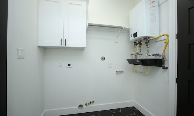 laundry area featuring tankless water heater, gas dryer hookup, cabinets, hookup for a washing machine, and dark tile patterned floors