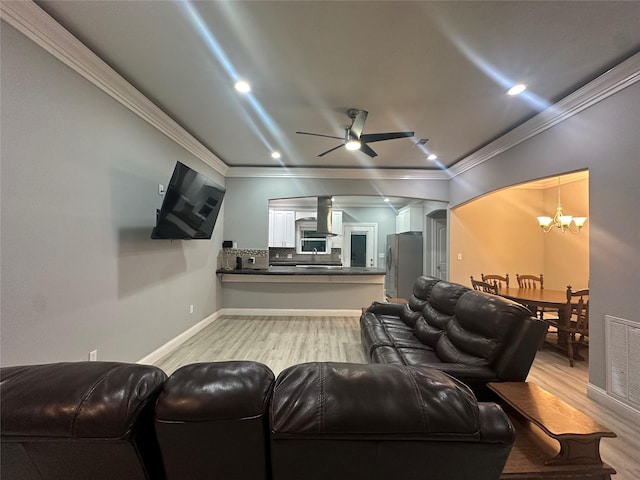 home theater room featuring ornamental molding, ceiling fan with notable chandelier, and light hardwood / wood-style flooring