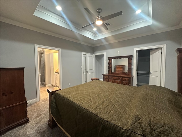 bedroom with ceiling fan, ensuite bathroom, ornamental molding, light carpet, and a raised ceiling