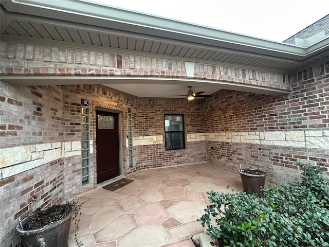 view of exterior entry with ceiling fan and a patio