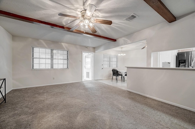 unfurnished living room featuring ceiling fan with notable chandelier, carpet floors, a textured ceiling, and beamed ceiling