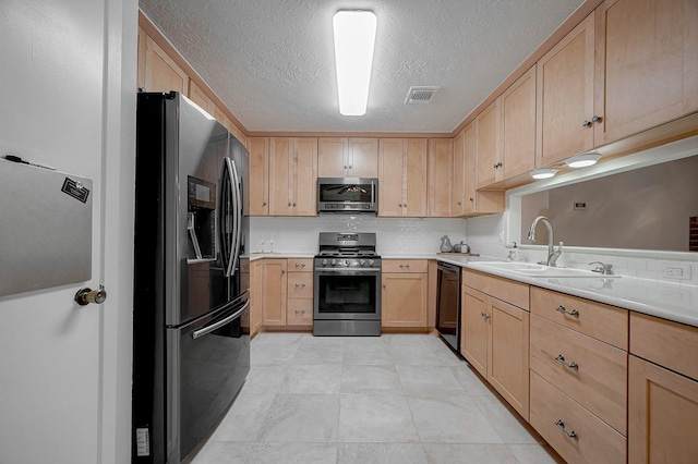 kitchen with sink, appliances with stainless steel finishes, a textured ceiling, decorative backsplash, and light brown cabinets