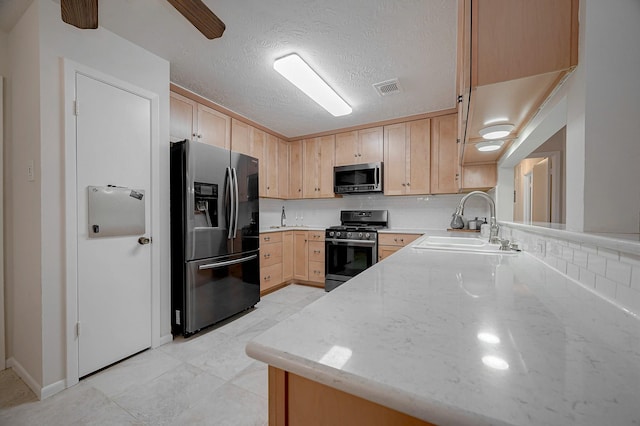 kitchen featuring sink, stainless steel appliances, light stone counters, a textured ceiling, and light brown cabinetry