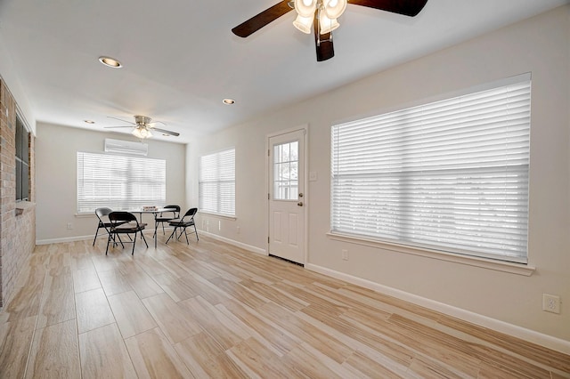 dining area with ceiling fan, light wood-type flooring, and a wall unit AC