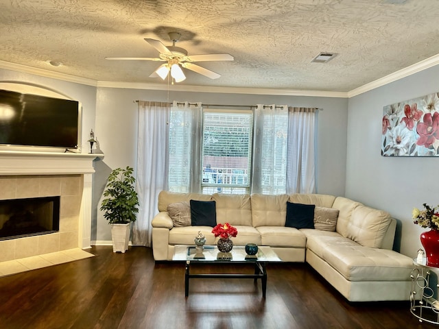 living room with dark wood-type flooring, ornamental molding, a fireplace, and a textured ceiling