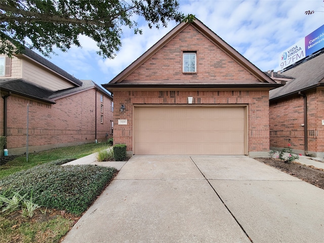 view of front of home with a garage, concrete driveway, brick siding, and fence