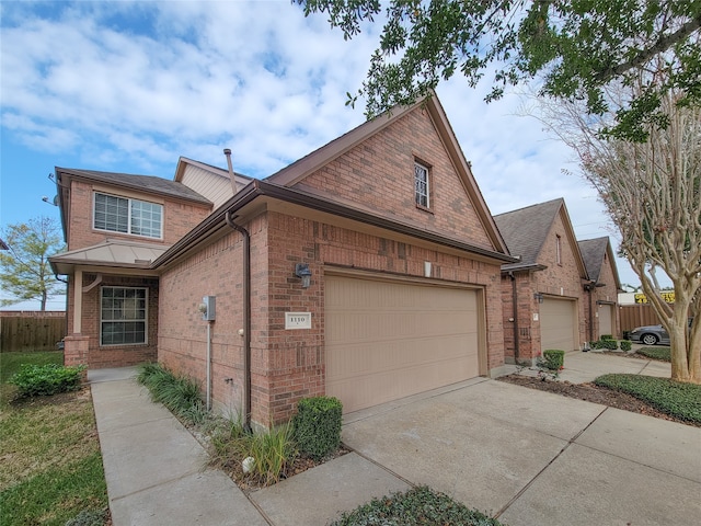 view of front of house with an attached garage, fence, concrete driveway, and brick siding