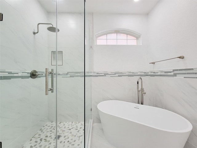 full bathroom with a stall shower, marble finish floor, a freestanding bath, and tile walls