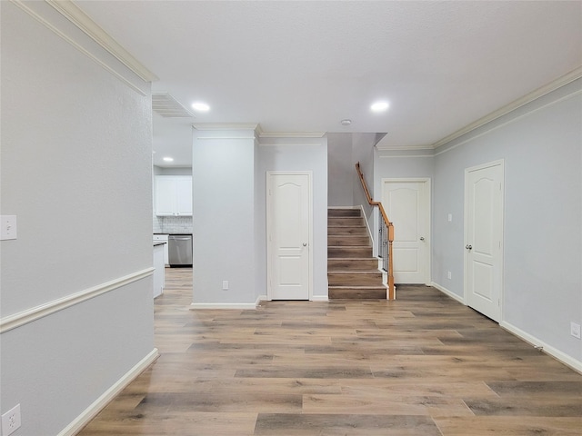 unfurnished room featuring light wood-style floors, crown molding, and stairs