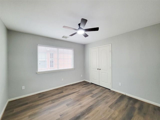 unfurnished bedroom featuring dark wood-type flooring, ceiling fan, and a closet