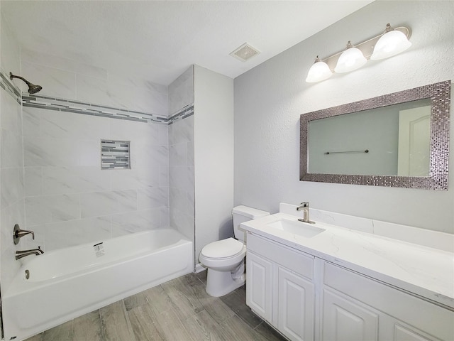 full bathroom featuring vanity, tiled shower / bath combo, and toilet