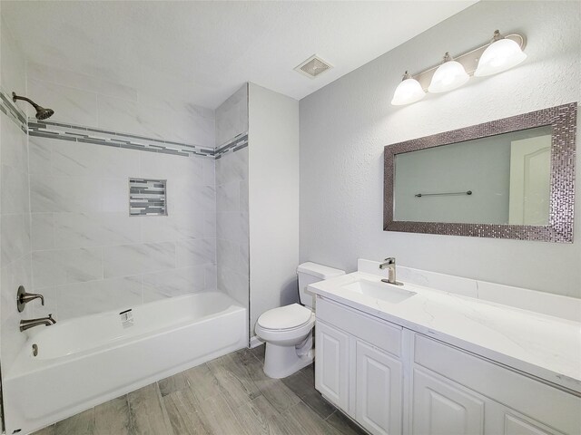 bathroom with wood finish floors, bathtub / shower combination, visible vents, toilet, and vanity