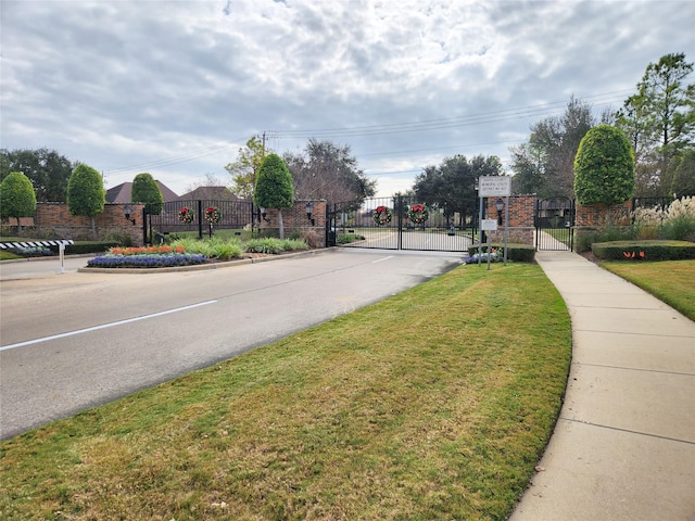 view of road featuring curbs, a gated entry, sidewalks, and a gate