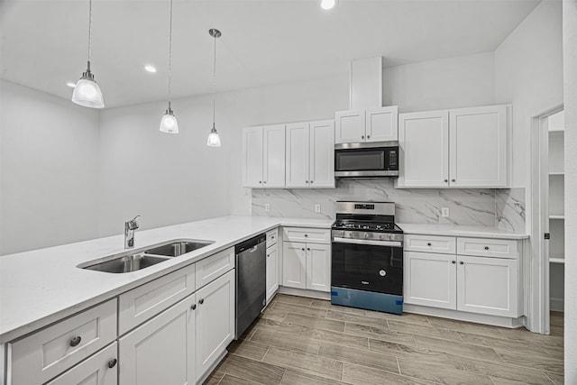 kitchen with pendant lighting, stainless steel appliances, sink, and white cabinets