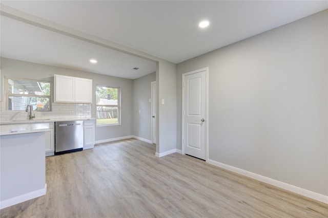 kitchen featuring sink, dishwasher, tasteful backsplash, light hardwood / wood-style floors, and white cabinets