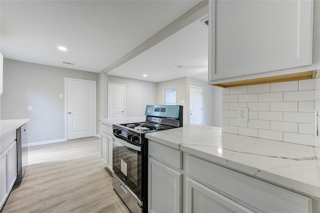 kitchen with white cabinetry, decorative backsplash, stainless steel appliances, light stone countertops, and light wood-type flooring