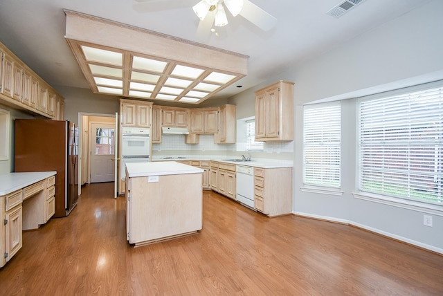 kitchen featuring light wood-type flooring, light brown cabinets, a kitchen island, white appliances, and backsplash