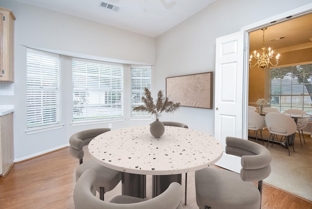 dining area with light wood-type flooring and an inviting chandelier